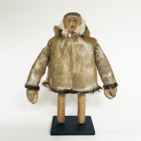 Carved wooden Eskimo man wearing a seal coat , upright on a meatal stand, early 20th century